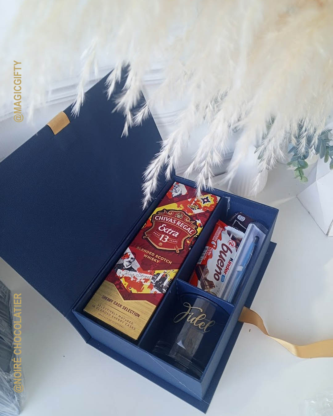Luxury box tipo libro con whisky premium, vaso con nombre, chocolates finos y detalle ejecutivo, ideal para celebrar sustentación de tesis.