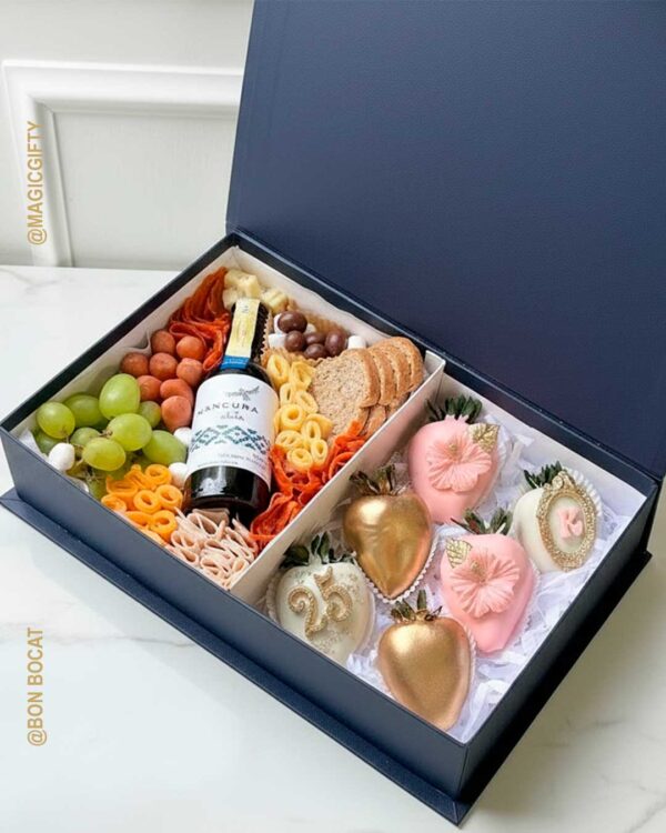 Grand Maison — caja azul navy tipo libro con charcutería, vino Mancura y fresas artesanales rosadas y doradas personalizadas