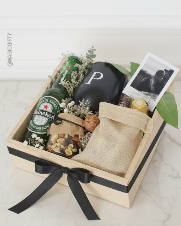 Gift box en bandeja de pino con cerveza Heineken, taza personalizada con inicial, foto Polaroid, snacks gourmet y decoración verde, cinta negra